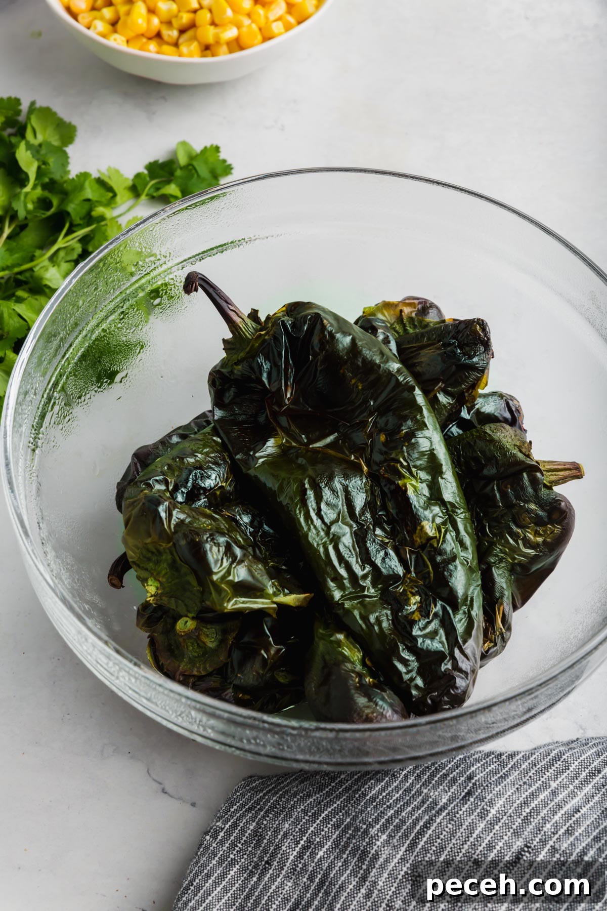 Roasted Chicken and Poblano Soup Recipe 4 A bowl of roasted poblano peppers with a bowl of corn in the background.