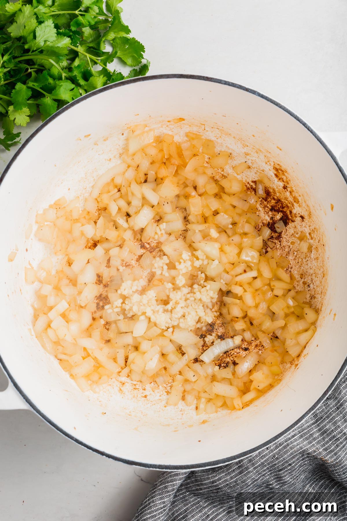 Roasted Chicken and Poblano Soup Recipe 7 An overhead view of a dutch oven with sautéed onion and minced garlic.