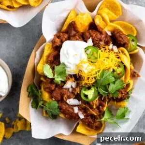 Boats of Frito pie served with sour cream, grated cheese, diced onion and slices of jalapeño.