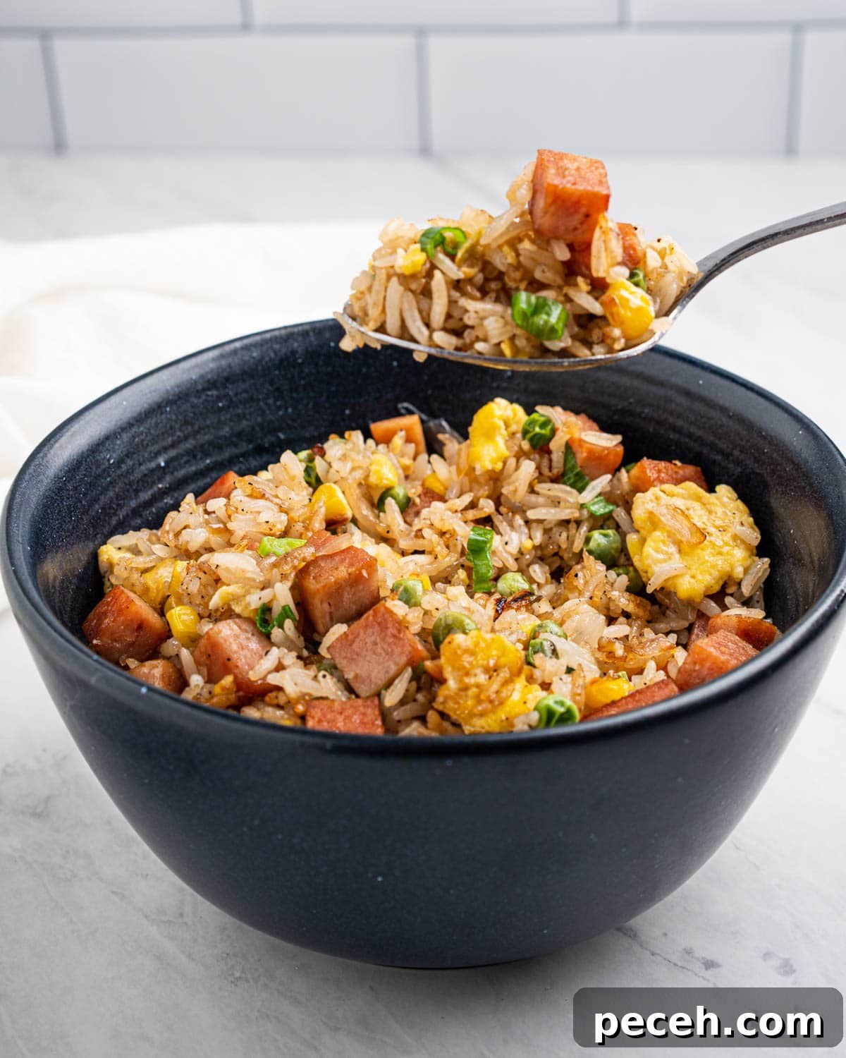 Crispy SPAM Fried Rice Recipe for Quick Weeknight Meals 11 Spoon scooping up spam fried rice from a bowl.