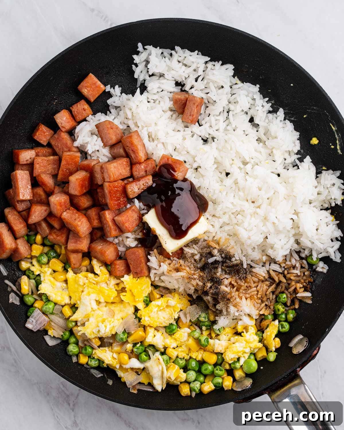 Crispy SPAM Fried Rice Recipe for Quick Weeknight Meals 8 Pan with sections of rice, vegetables, scrambled eggs, spam, seasoning, and butter.