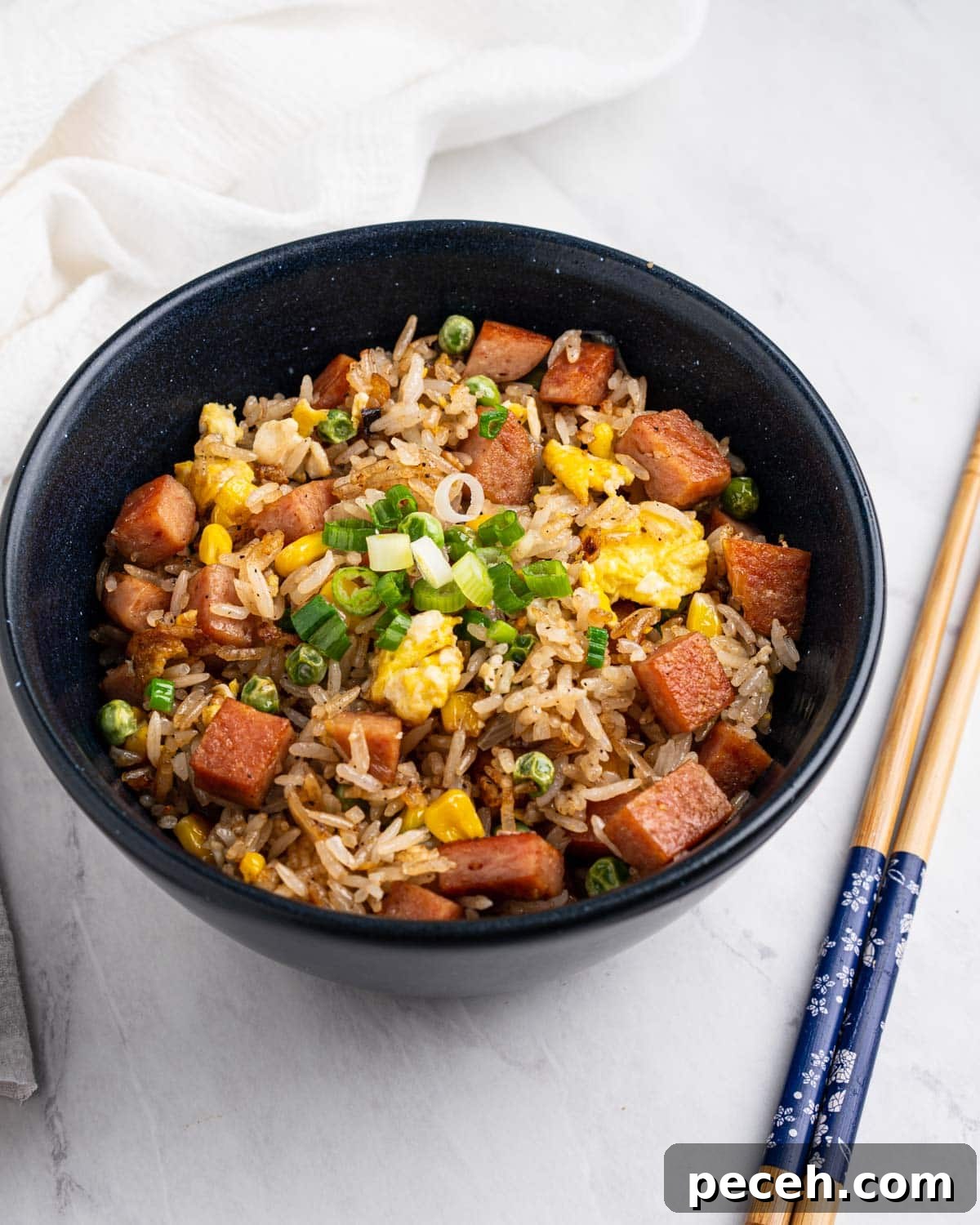 Crispy SPAM Fried Rice Recipe for Quick Weeknight Meals 10 Spam fried rice in a bowl with chopsticks on the side.