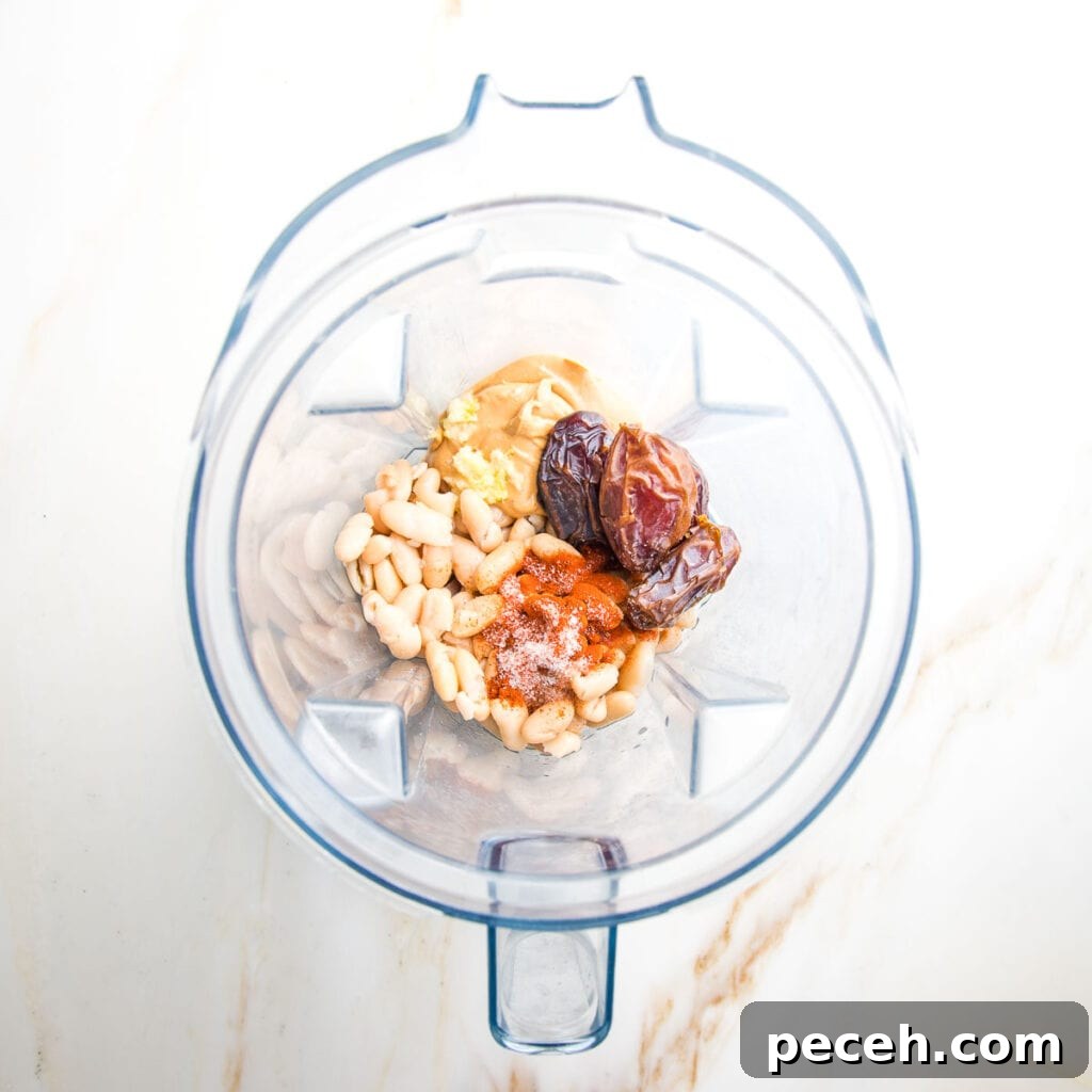 Smoky Chipotle Salad Dressing Recipe: Zesty, Creamy, & Homemade 4 Blender pitcher filled with ingredients: white beans, dates, cashew butter, spices, garlic, vinegar.