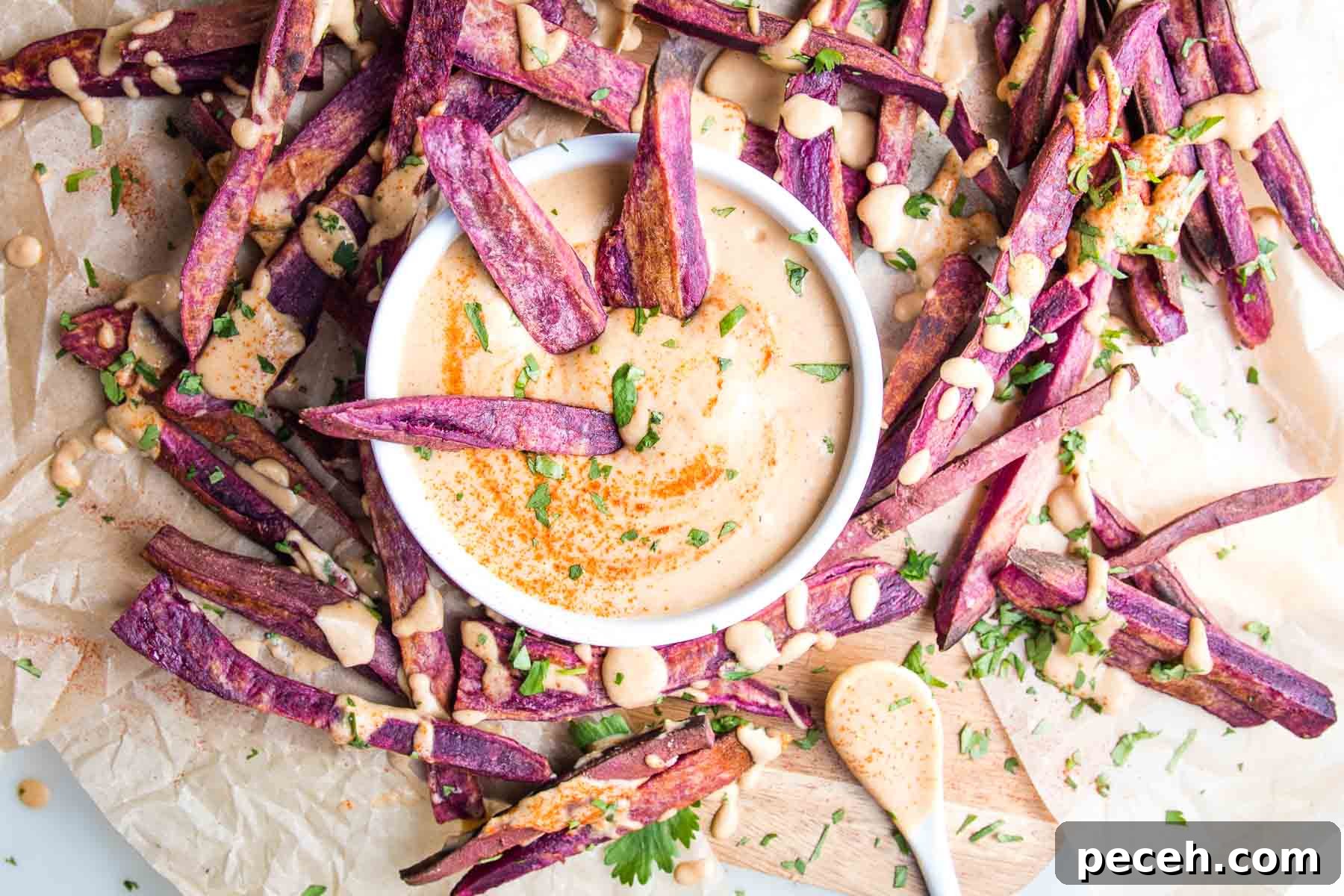 Smoky Chipotle Salad Dressing Recipe: Zesty, Creamy, & Homemade 9 Purple sweet potato fries on unbleached parchment with a dish of chipotle dipping sauce and same orange sauce is drizzled over the fries.