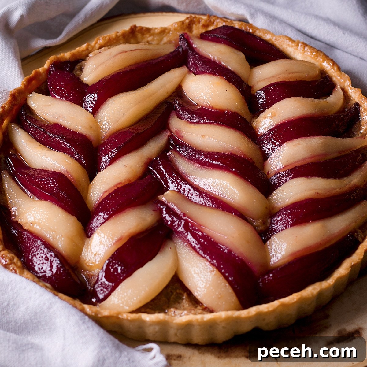 A poached pear and frangipane tart on a wood serving platter.