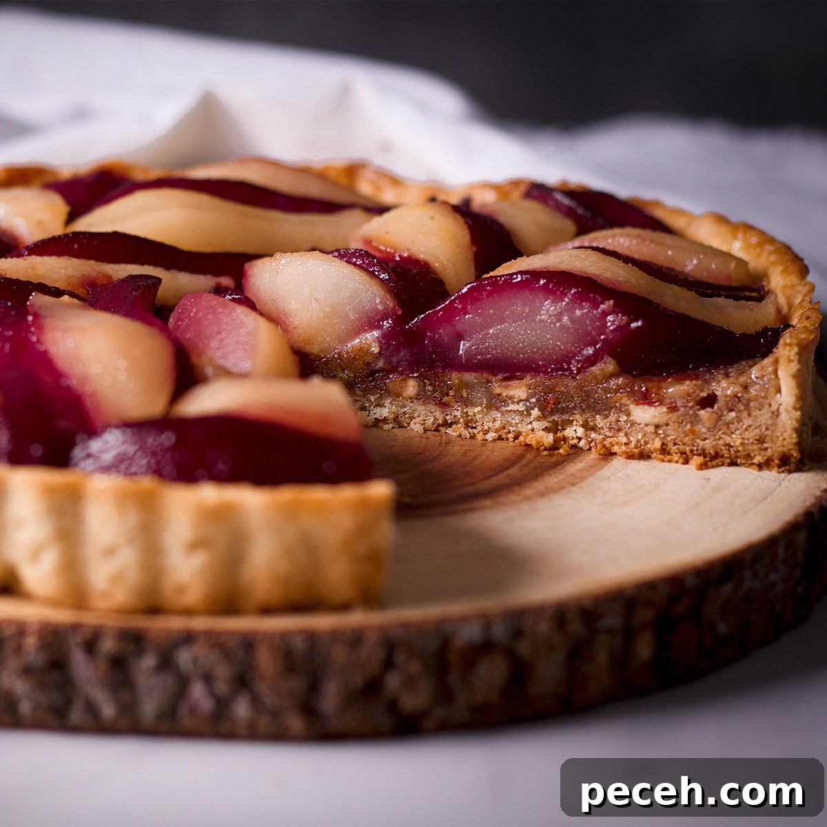 A poached pear and frangipane tart with a slice removed from it.