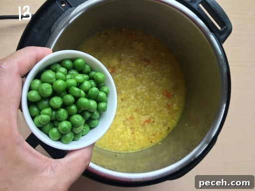 Adding peas to the vegetable Daliya Khichdi 