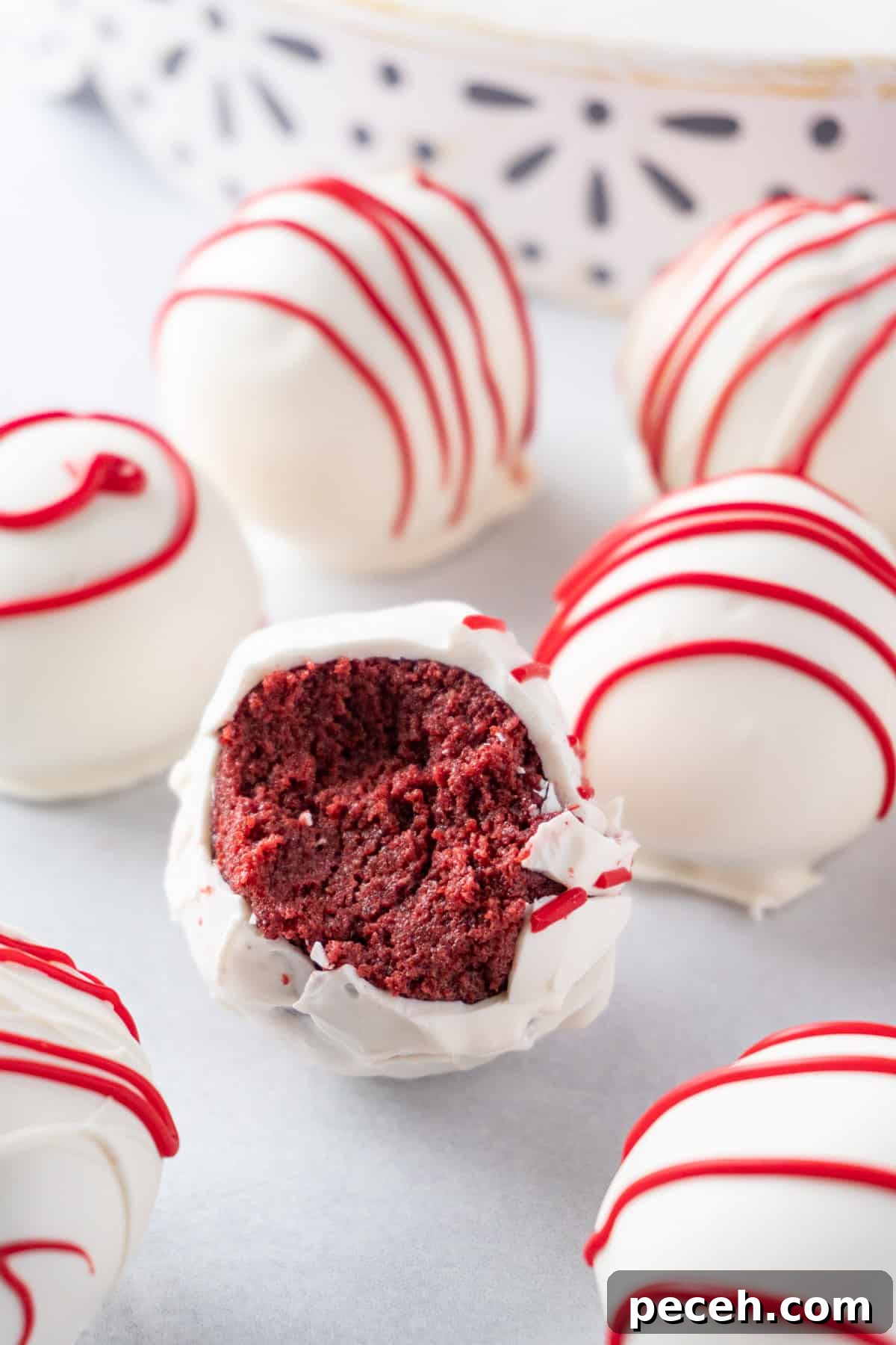 red and white red velvet cake balls  with one with a bite taken out.