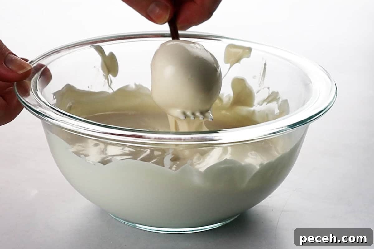 cake ball on fork being dipped into melted candy melts.