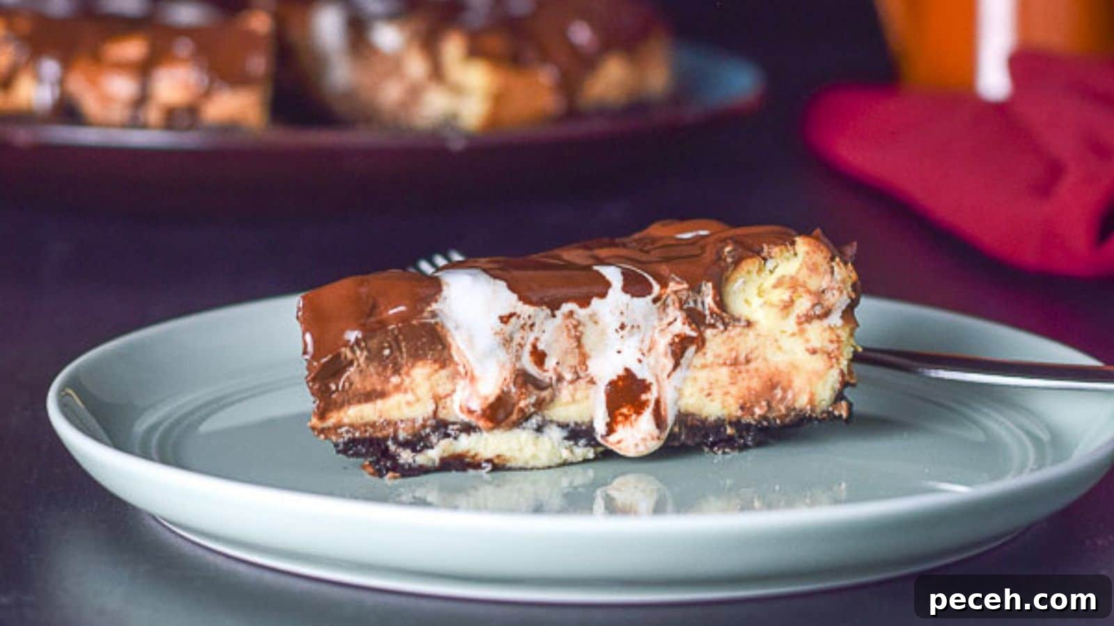 Decadent Rocky Road Cheesecake Recipe for Chocolate Lovers 3 A slice of cheesecake on a green plate with marshmallow and chocolate with the cake in the back