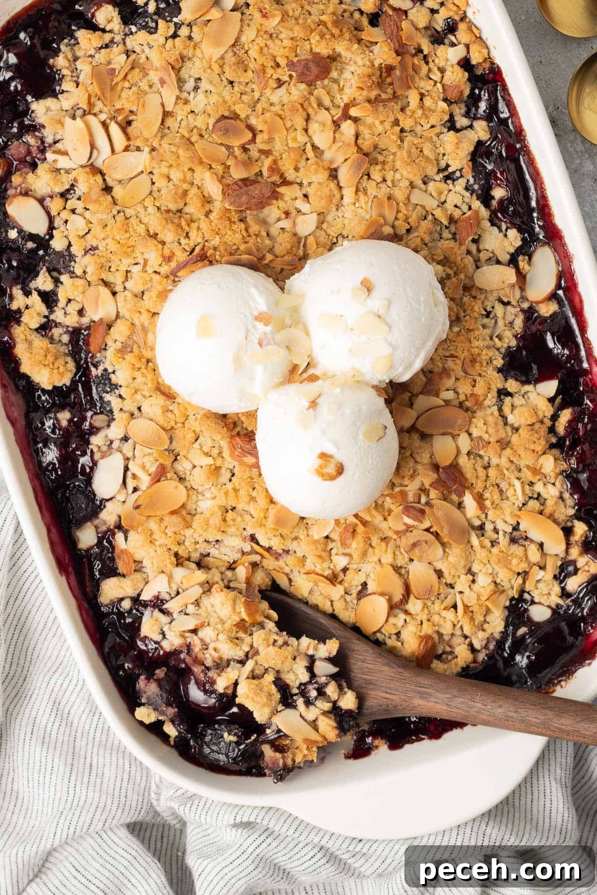 A spoon resting in a baking dish filled with cherry crisp.