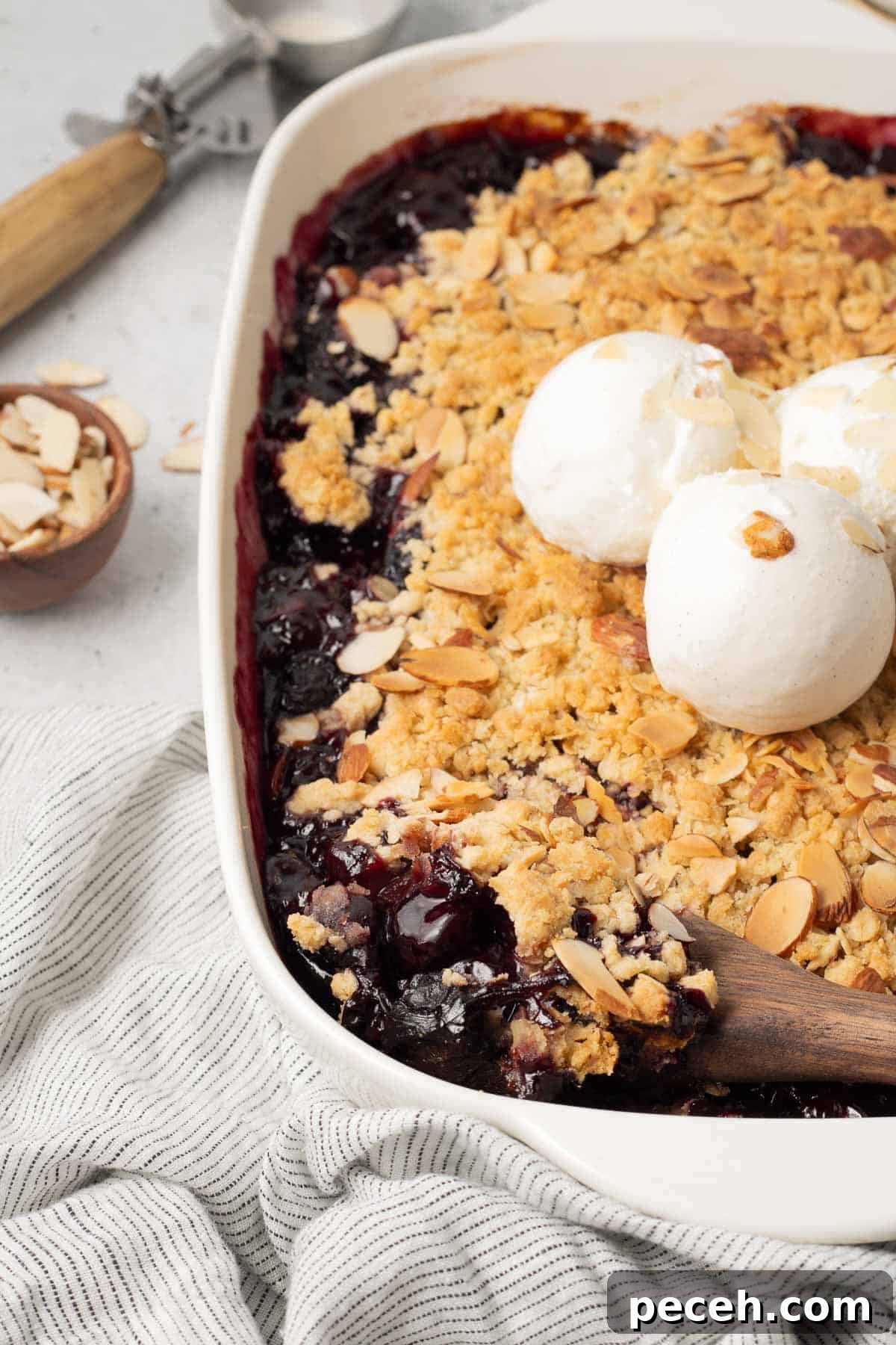 A spoon resting in a baking dish filled with cherry crisp.