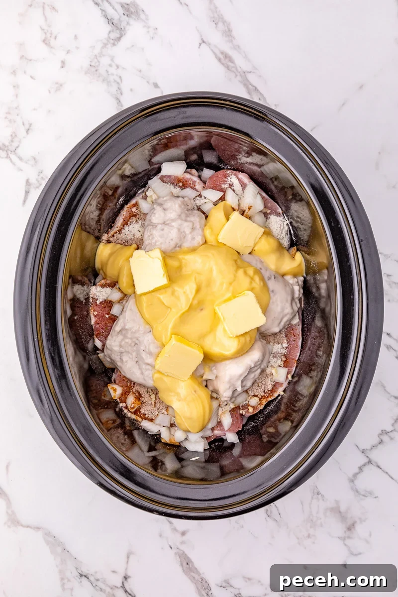 Cream of mushroom soup and cream of chicken soup is added to the top of the pork chop mixture in crockpot.