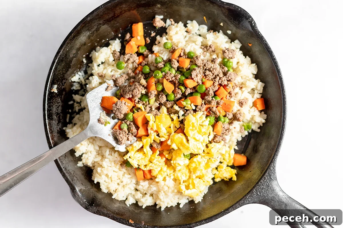 Ground Beef Fried Rice Recipe: Flavorful One-Pan Dinner 8 Ground beef, eggs and vegetables added to rice in cast iron skillet.