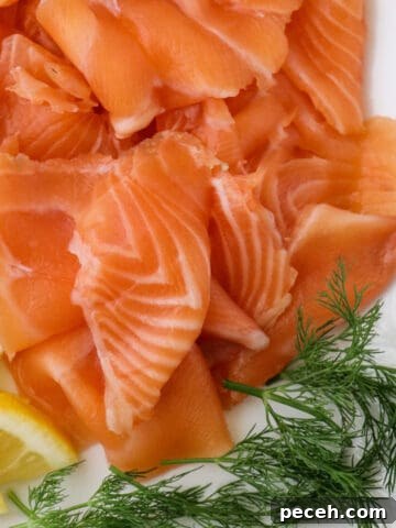 Close up of gravlax on a white platter with dill and lemons.
