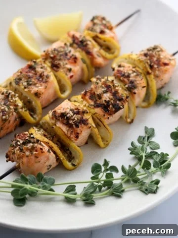 Salmon skewers on a plate with lemon and fresh herbs