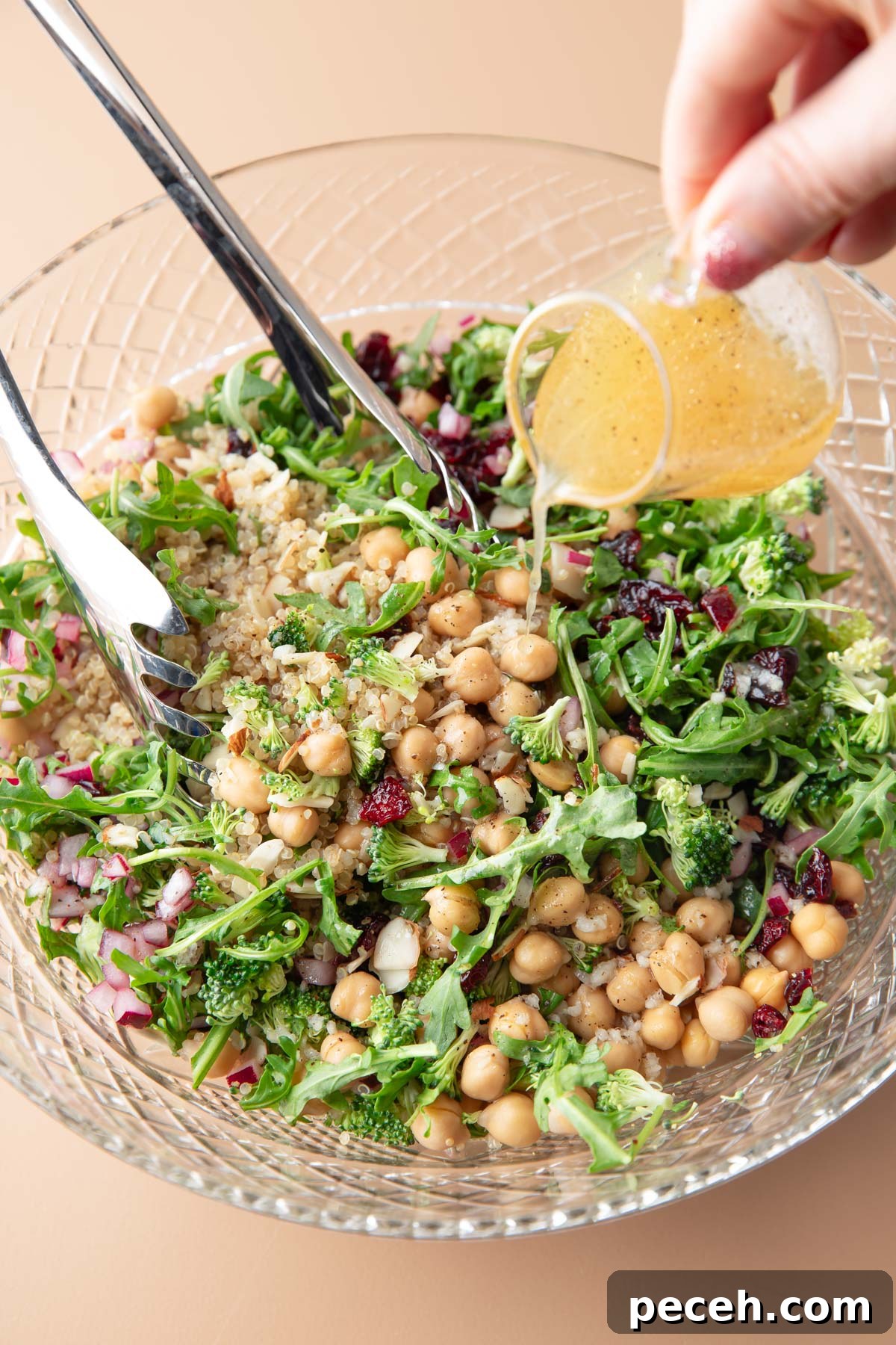 Lemony Quinoa and Arugula Salad with Cherry Tomatoes 2 lemon vinaigrette dressing poured over serving bowl of quinoa arugula salad with almonds and dried cranberries