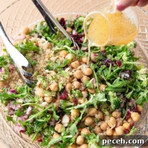 Lemony Quinoa and Arugula Salad with Cherry Tomatoes 7 lemon vinaigrette dressing poured over serving bowl of quinoa arugula salad with almonds and dried cranberries