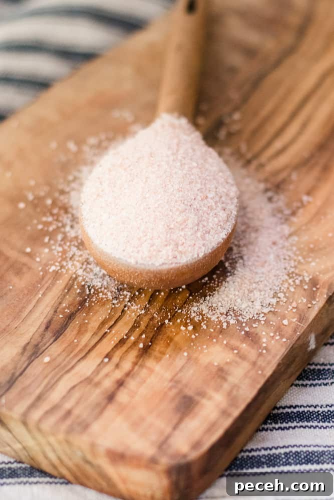 Himalayan Pink Salt Uses: 12 Practical Ways to Use It at Home 5 Pink Himalayan salt spilling out of wooden measuring spoon.