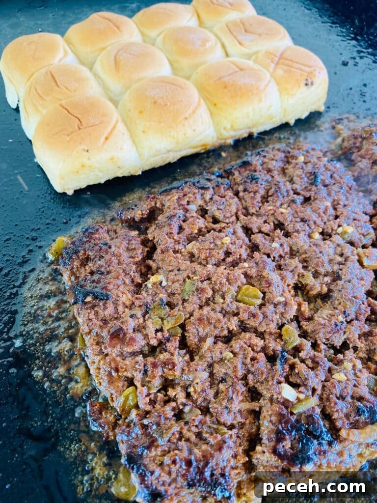 burger cooking on the griddle with slider buns Blackstone Taco Burger Sliders