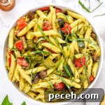 roasted veggie pesto pasta salad in a bowl with basil on top.