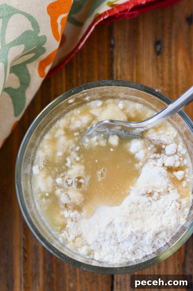 A small bowl of flour being mixed into chicken stock.