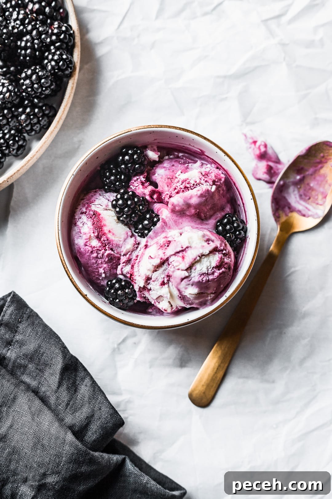 Honey-Blackberry Mascarpone Ice Cream Recipe 3 Bowl of purple and white ice cream scoops topped with blackberries and gold spoon nearby