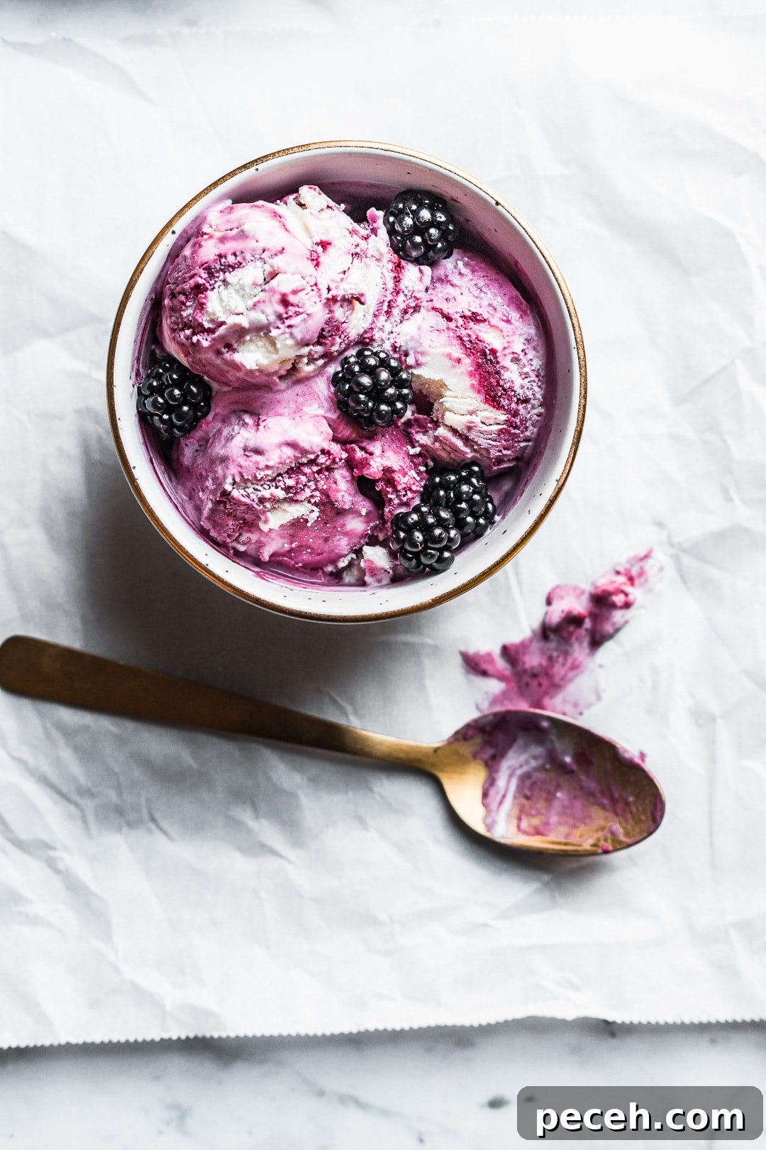 Honey-Blackberry Mascarpone Ice Cream Recipe 7 Bowl of honey blackberry mascarpone ice cream scoops with blackberries on top and gold spoon nearby