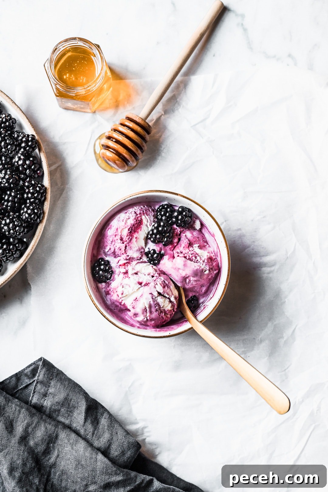 Honey-Blackberry Mascarpone Ice Cream Recipe 9 Three scoops of purple and white swirled ice cream in a bowl with honey and blackberries nearby