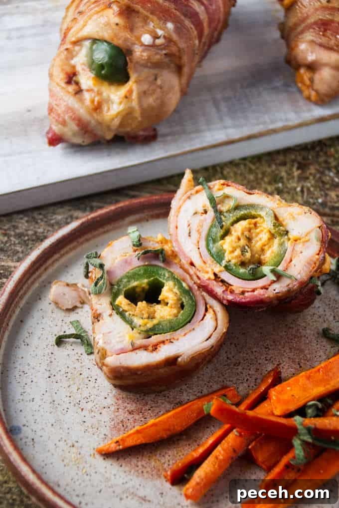 Smoked Jalapeño Popper Stuffed Chicken Recipe 6 Smoked jalapeño popper stuffed chicken breast sliced and plated with some air fryer carrots with two unsliced pieces of chicken in background.