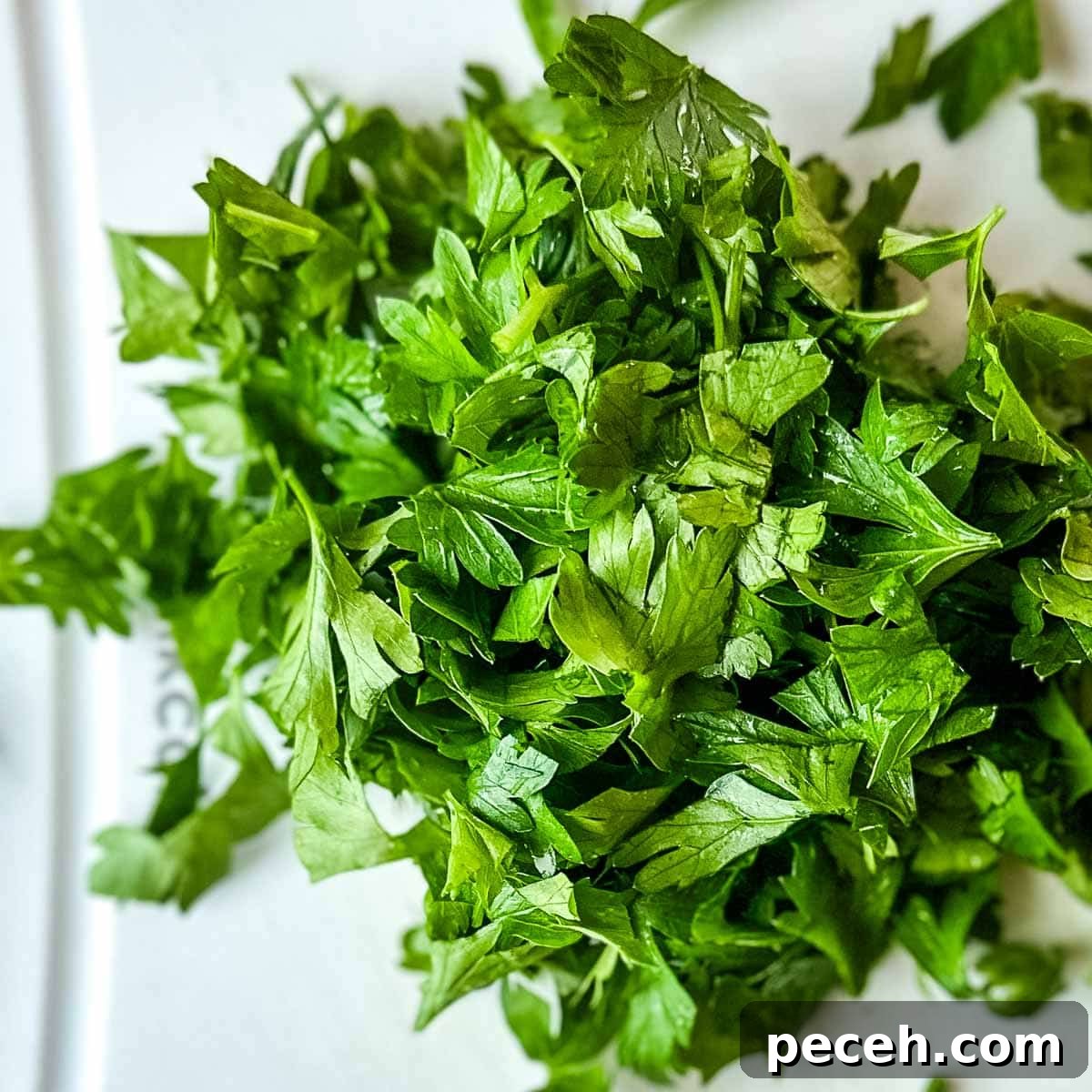 Cilantro Chimichurri Sauce: Zesty Recipe for Grilled Meats and Veggies 5 Chopped parsley on a white cutting board.
