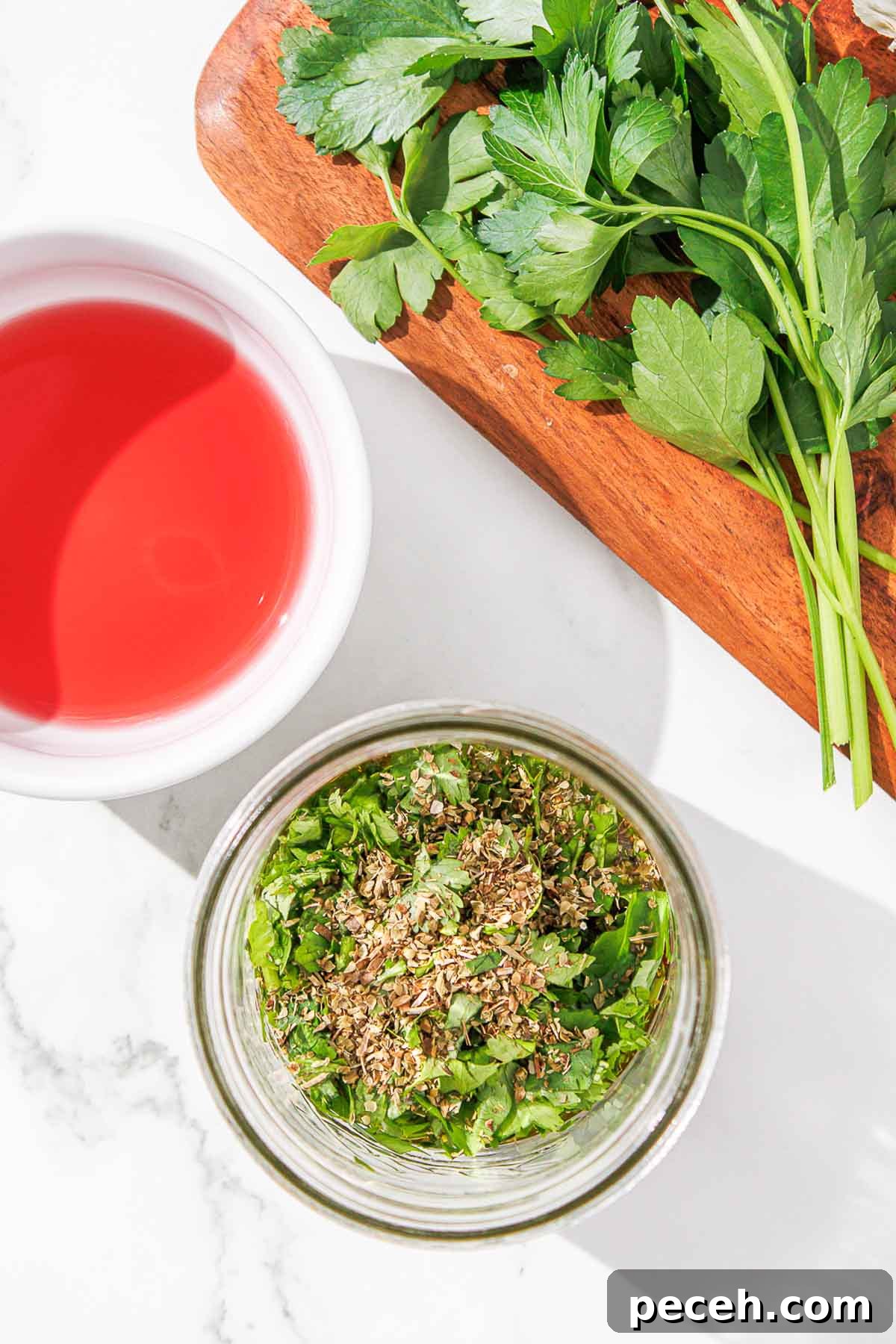 Cilantro Chimichurri Sauce: Zesty Recipe for Grilled Meats and Veggies 7 A bowl of chopped herbs and dried oregano beside a bowl of vinegar.