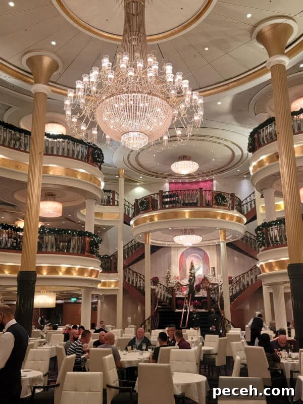 3-Night Royal Caribbean Navigator of the Seas Cruise to Ensenada 8 Large crystal chandelier hanging over white tables and chairs with multiple staircases in the background