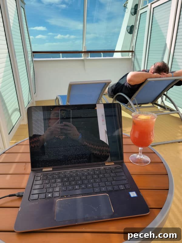 3-Night Royal Caribbean Navigator of the Seas Cruise to Ensenada 12 Tammilee taking a photo of a laptop next to a tropical drink with john lounging on a lounge chair with the ocean in the distance