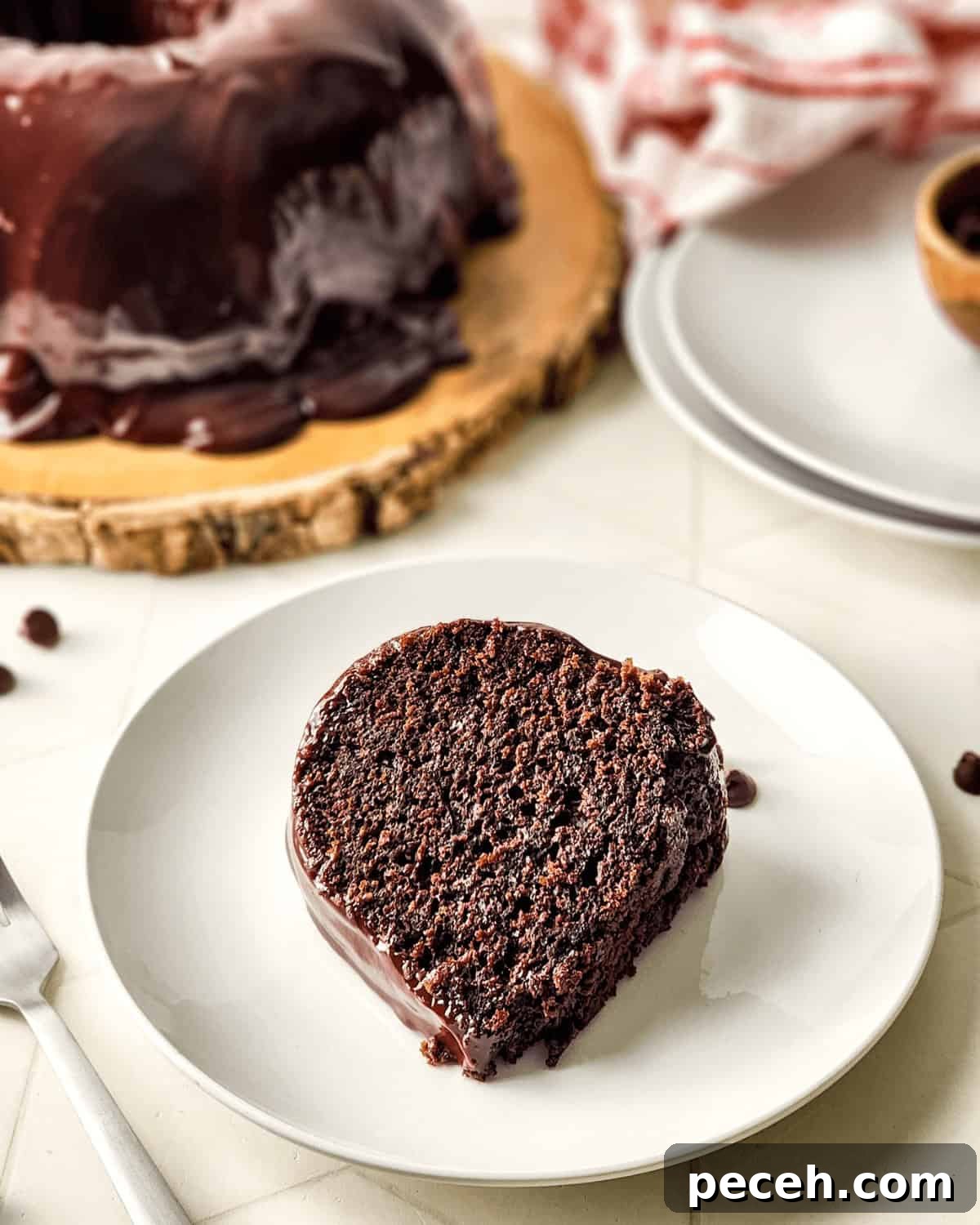 Moist Chocolate Chip Bundt Cake Recipe You’ll Love 9 Slice of chocolate chip Bundt cake with ganache on a white plate, with the remaining cake in the background.