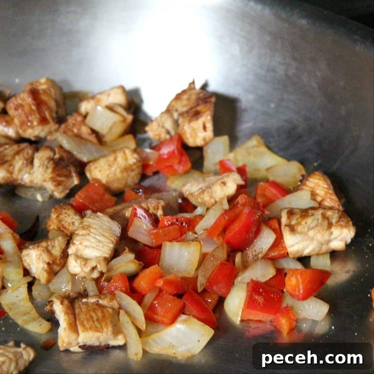 pan fried chicken, peppers, and onions for Cajun Alfredo recipe chicken, peppers, and onions in pan