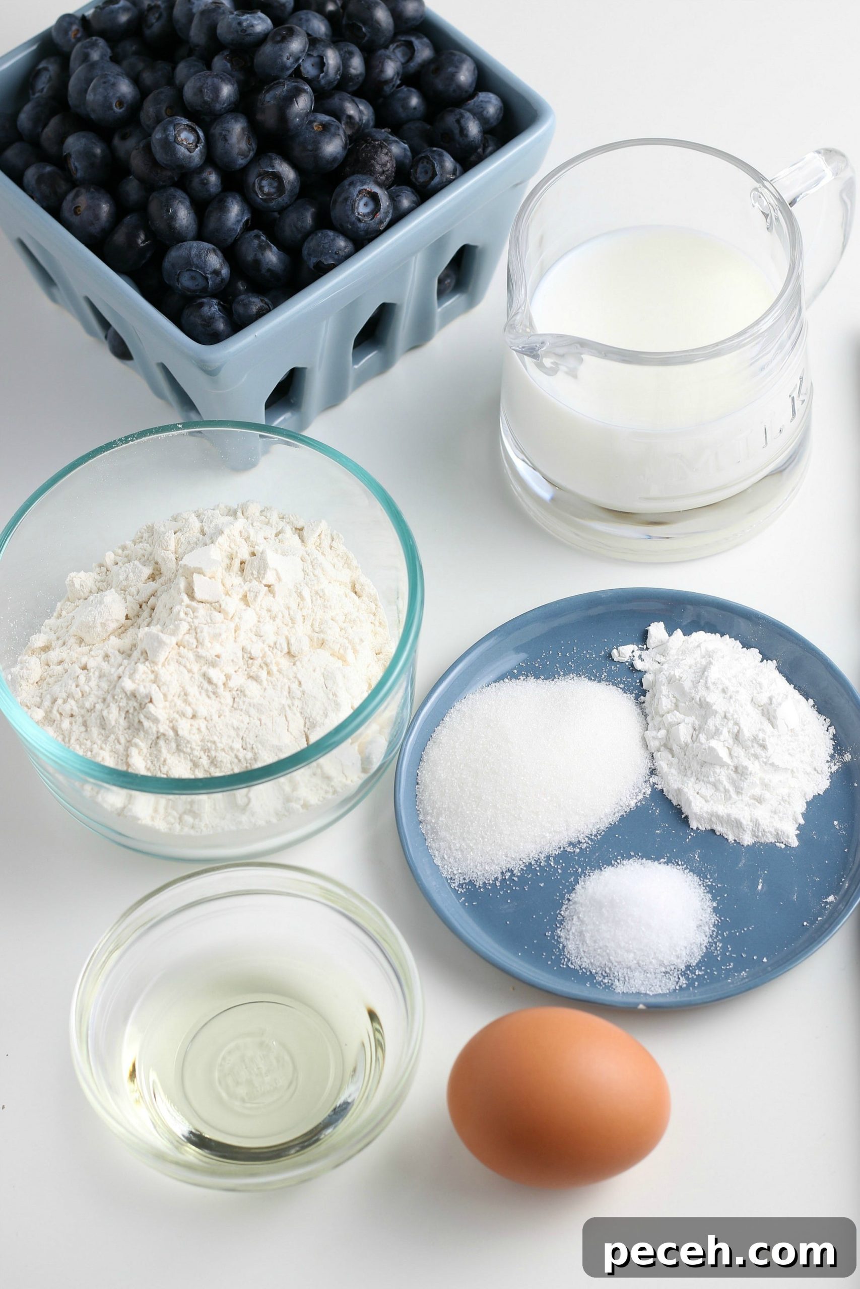 Homemade Blueberry Pancake Recipe for Fluffy, Perfect Stacks 3 ingredients for homemade blueberry pancakes on a white countertop