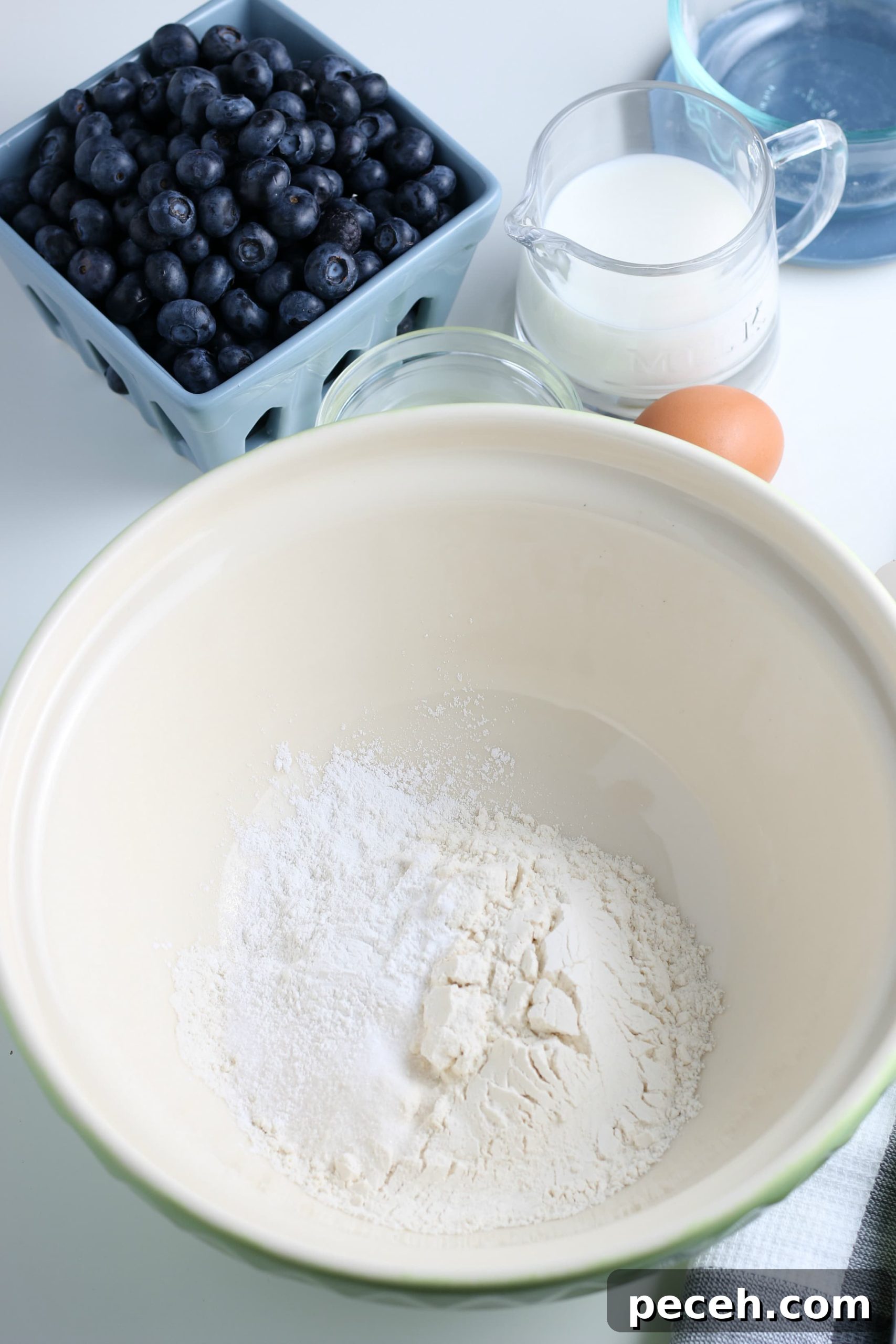 Homemade Blueberry Pancake Recipe for Fluffy, Perfect Stacks 4 white glass bowl filled with dry ingredients for blueberry pancakes.