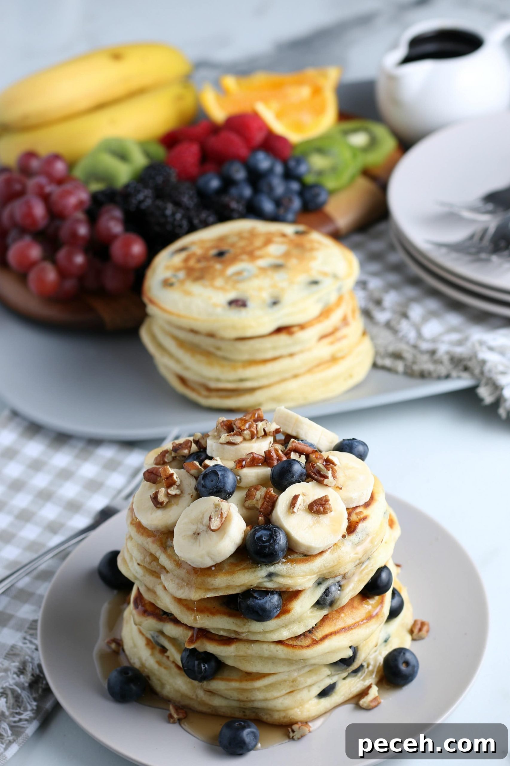 Homemade Blueberry Pancake Recipe for Fluffy, Perfect Stacks 7 A stack of blueberry pancakes with fruit in the background.