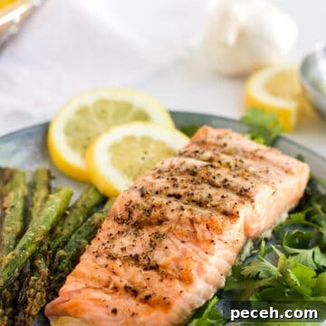 Perfectly Grilled Salmon with Crispy Skin and Lemon Herb Rub 11 Grilled salmon on a bed of herbs with slices of lemon in the background.