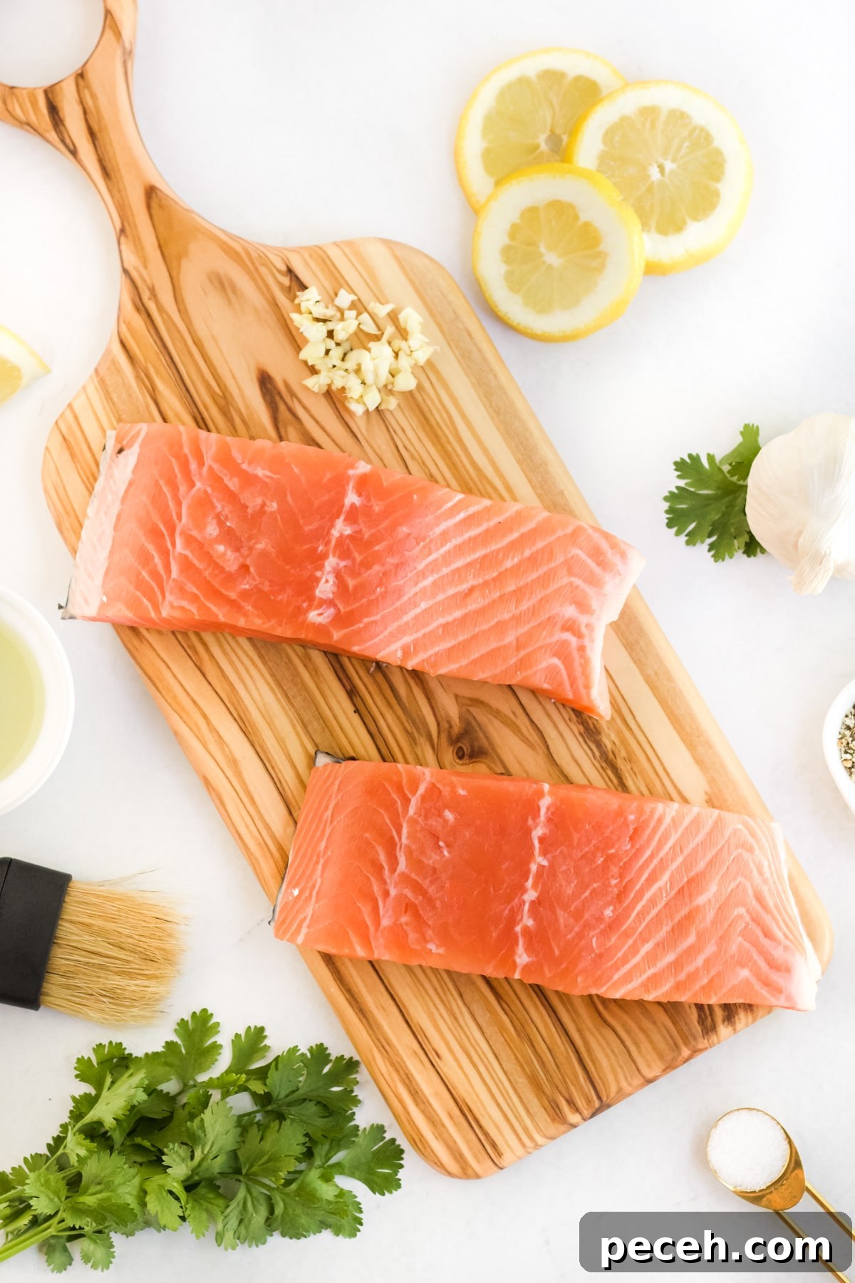Perfectly Grilled Salmon with Crispy Skin and Lemon Herb Rub 3 Raw salmon being prepared for the grill on a cutting board will all the ingredients around it.