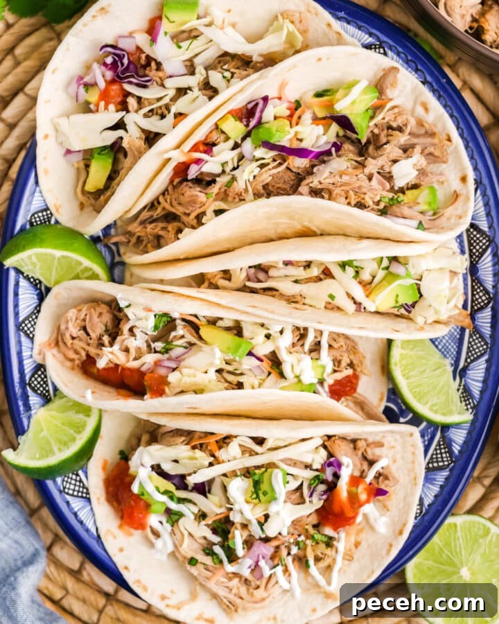 A plate with pulled pork tacos with lime garnish.