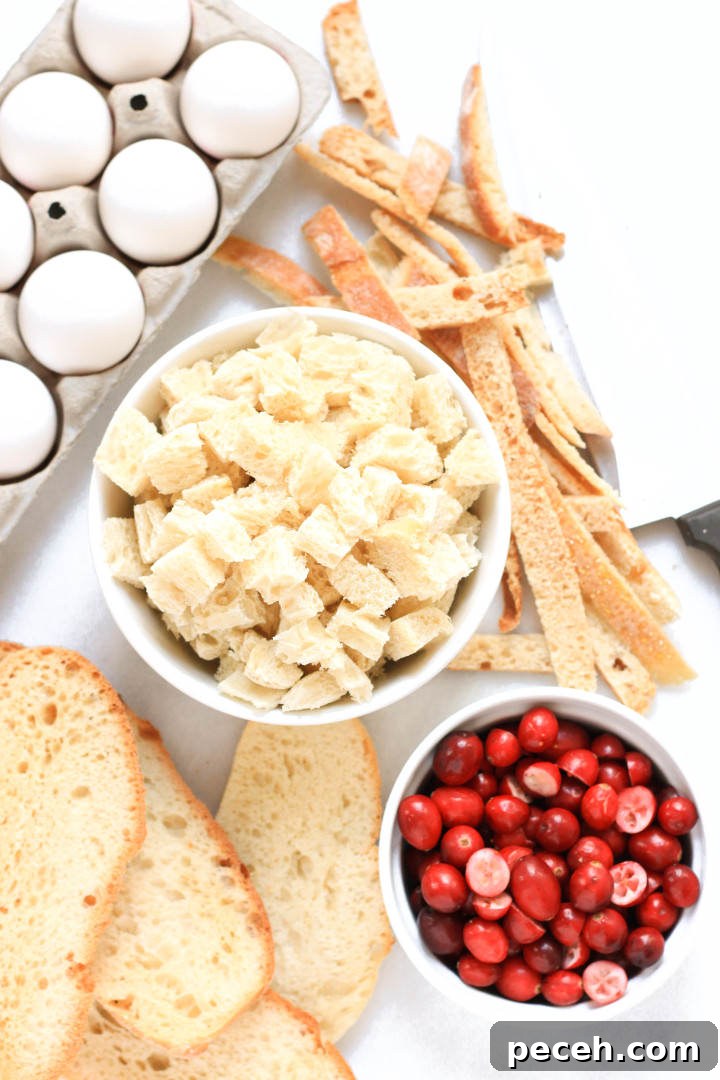Cranberry Bread Pudding (Gluten-Free, Dairy-Free) Bread cubes, slices of bread, fresh cranberries and eggs laid out on a marble board.