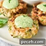 Chicken patties on a white plate topped with a green sauce.