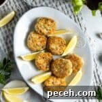 Chicken patties on a white plate with lemon wedges.