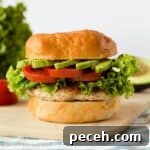 Ground chicken burger on a bun with lettuce tomato and avocado.