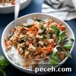 Thai basil chicken over white rice in white bowl.
