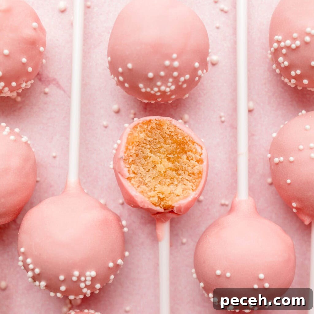 Several gluten-free pink cake pops lined up on pink surface, one with bite taken.