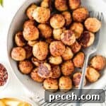 A bowl full of gluten-free baked chicken meatballs on white wooden surface next to a bowl of pasta.