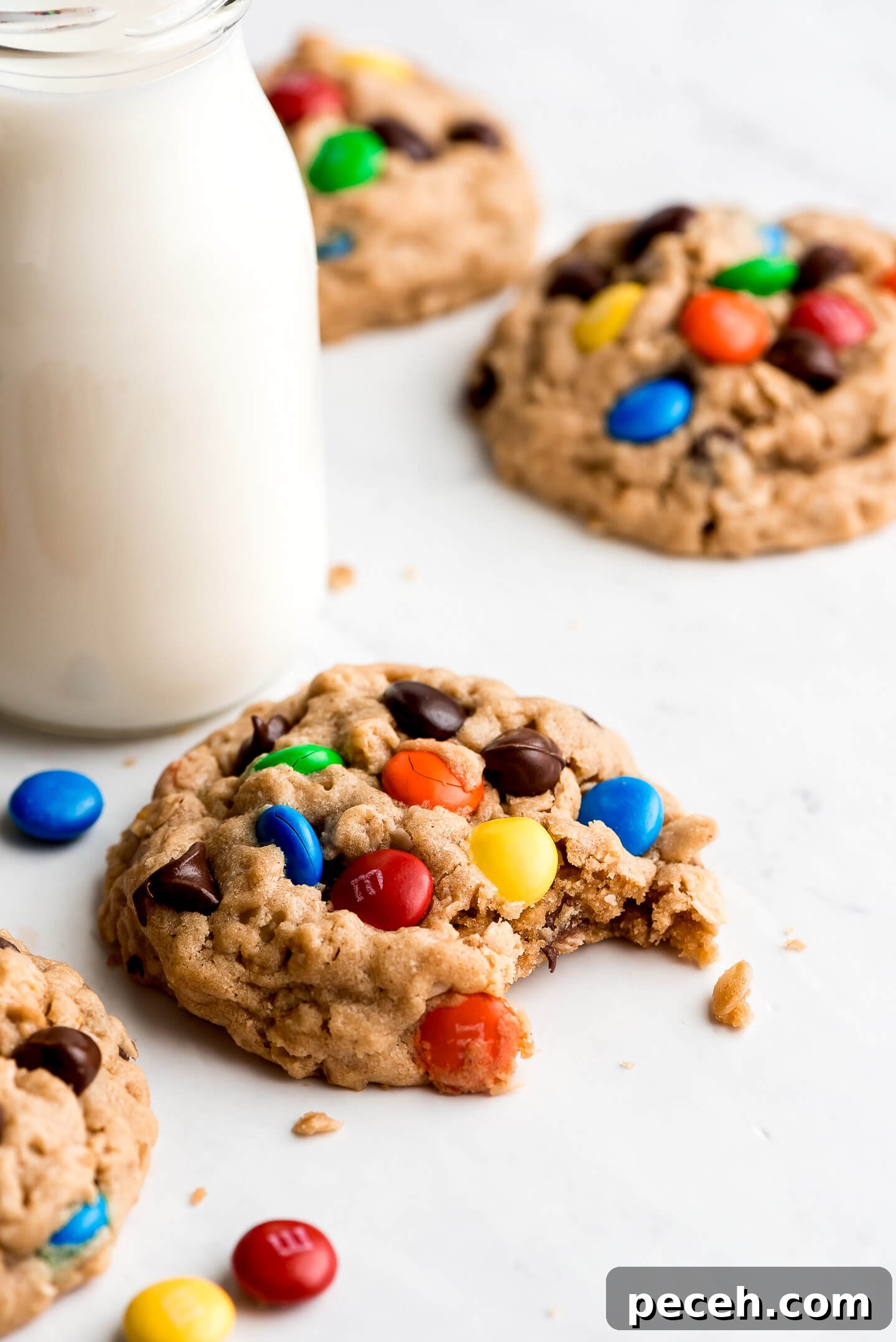 Soft Chewy Monster Cookies Recipe – Loaded Chocolate Chip Cookies 6 A Monster Cookie with M&M's and Chocolate Chips on top with a bite taken out and a glass of milk on the side.